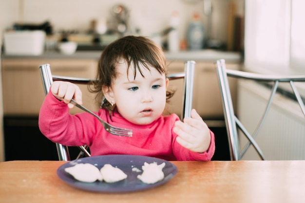 niña en la mesa come albóndigas por su cuenta