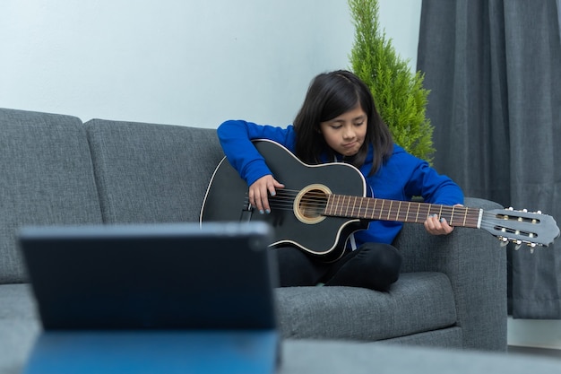Niña mexicana frustrada tomando lecciones de guitarra en casa debido al encierro por coronavirus, educación en casa
