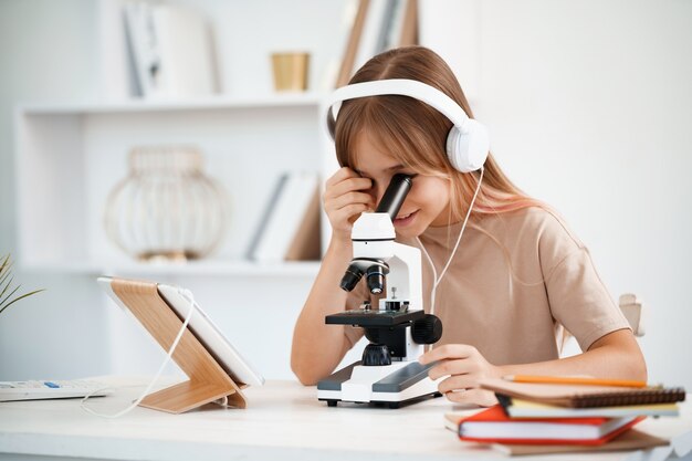 Niña con microscopio durante la educación de lecciones en línea en casa