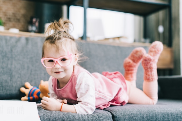 La niña miente en el sofá y sonriendo