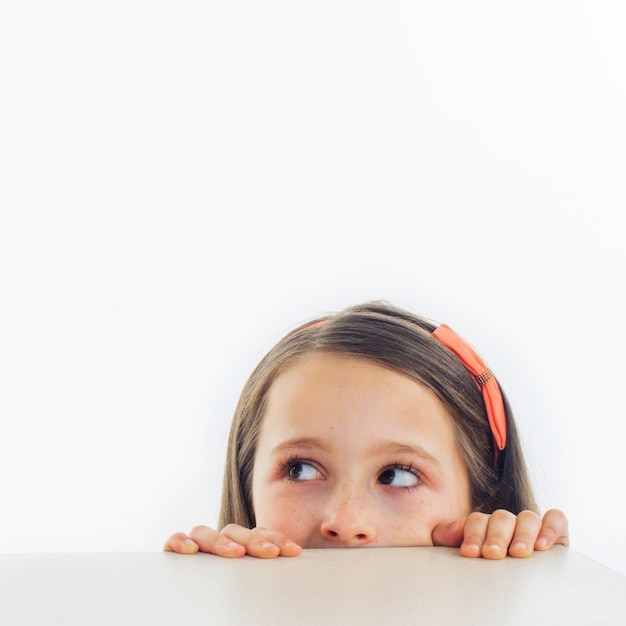 Niña mira el borde de una mesa