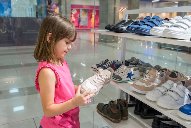 Una niña mira zapatos en un centro comercial Compras