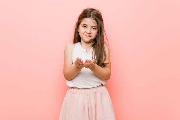 Niña con una mirada de princesa sosteniendo algo con palmeras, ofreciendo.