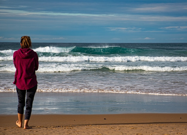 Una niña mirando al mar en un día soleado.