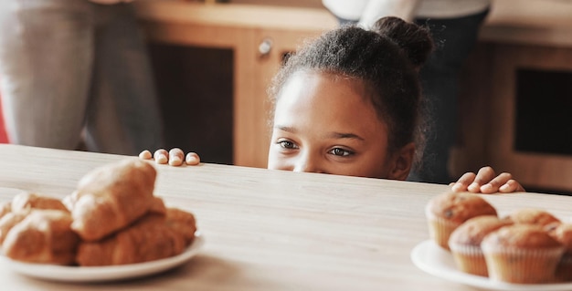 Niña mirando con deseo a los dulces en la cocina