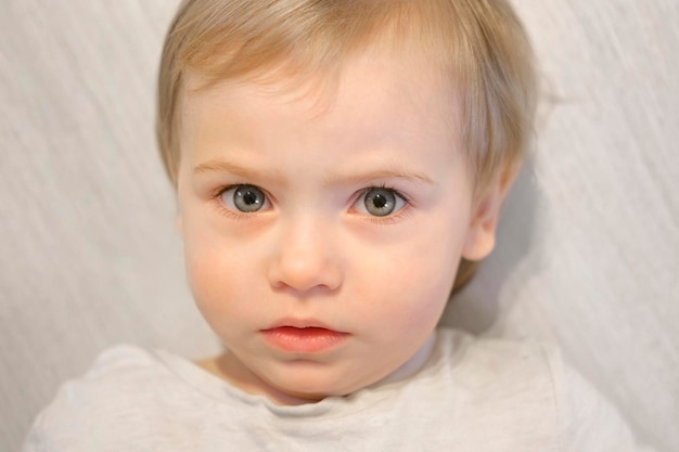 Niña mirando fijamente a la cámara. Su mirada es curiosa. Ojos bien abiertos. Mirada fija. Primer plano de la cara del niño bebé sobre fondo claro. Expresión facial de emoción infantil. 1 año de edad.