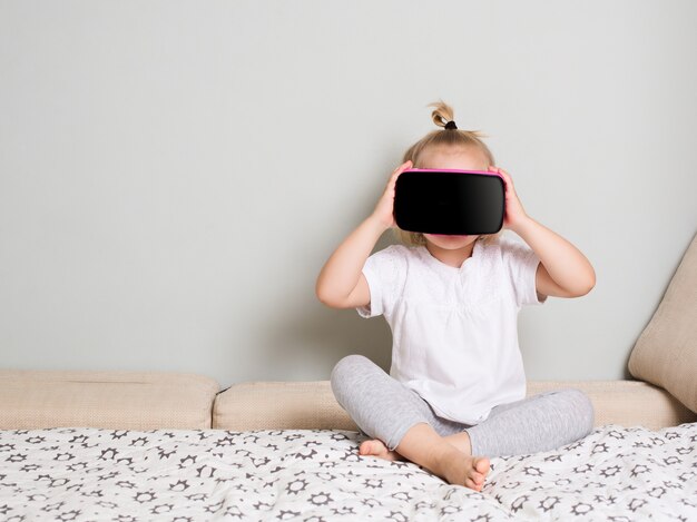 Niña mirando con gafas de realidad virtual en casa. Interior escandinavo