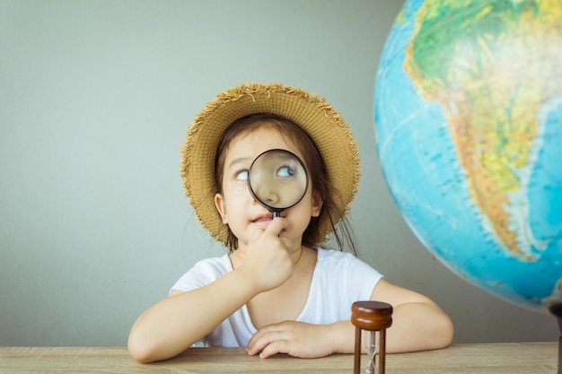Niña mirando el globo a través de una lupa en la mesa