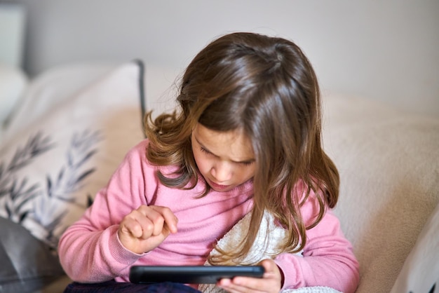 Niña mirando hacia otro lado mientras está sentada en el teléfono móvil.