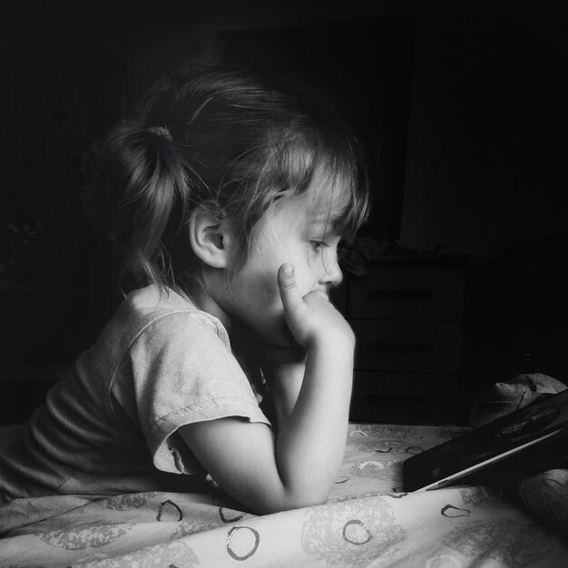 Foto niña mirando el teléfono móvil en casa