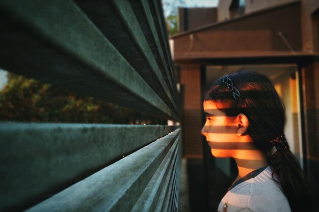 Foto niña mirando a través de la barandilla en un día soleado