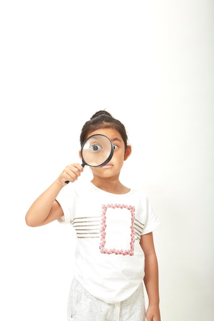 Foto niña mirando a través de una lupa contra un fondo blanco