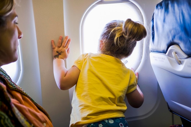 Niña mirando por la ventana del avión