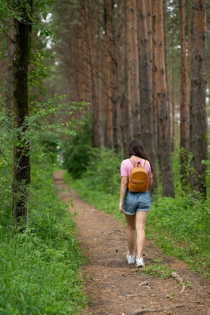 Foto una niña con una mochila detrás de los hombros camina por un sendero forestal