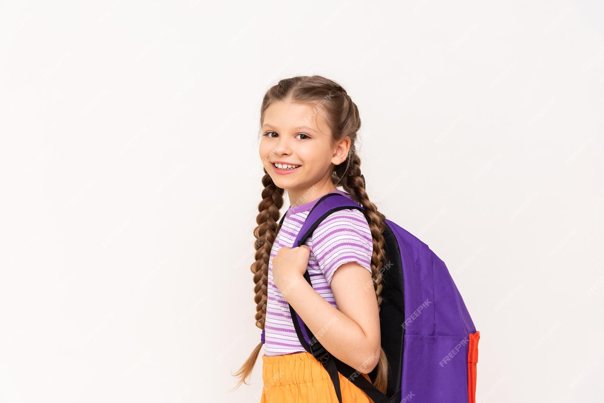 Una niña con una mochila en la espalda con naranjas sobre un fondo blanco aislado cursos educativos para niños | Foto Premium