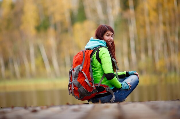 Niña, con, mochila, sentado, en, puente, en, lago