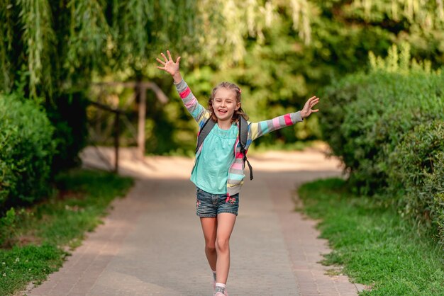 Niña con mochila yendo a casa después de la escuela a lo largo de Park Road