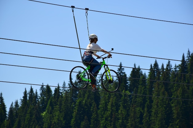 Una niña monta una bicicleta en la cuerda floja con casco y gafas de sol y se toma una selfie