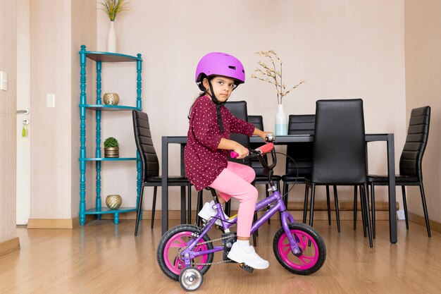 Niña monta una bicicleta en su sala de estar