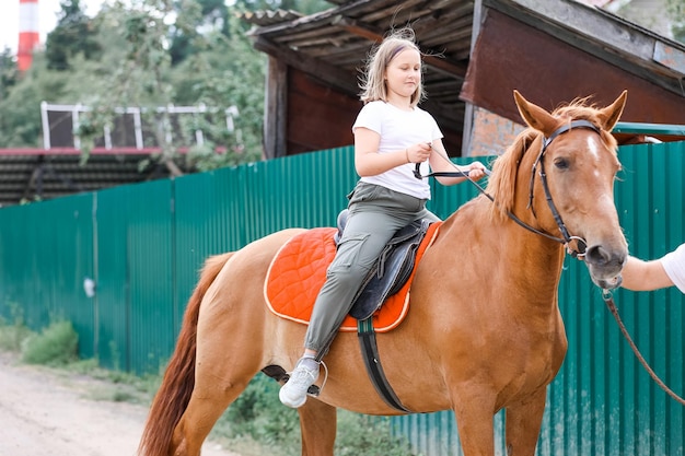 Una niña monta un caballo en el caluroso verano.