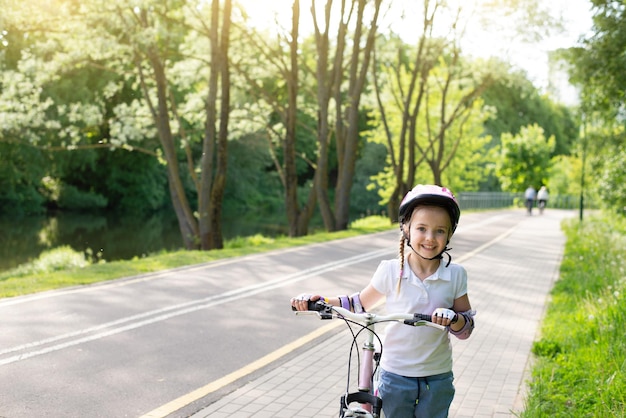 Niña montando en bicicleta en un carril bici en la ciudad y en el parque