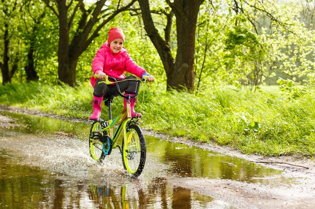 niña montando bicicleta en un charco de agua