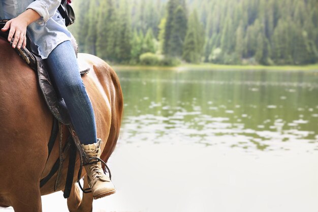 Foto niña montando a caballo cerca del lago