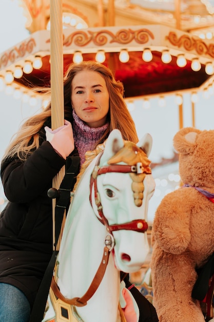 niña montando un carrusel con caballos