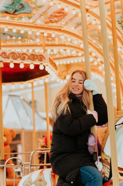 niña montando un carrusel con caballos