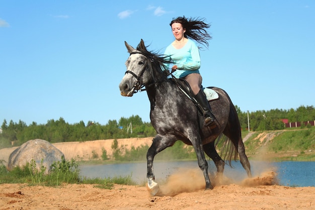 Niña montando rápido en un caballo gris