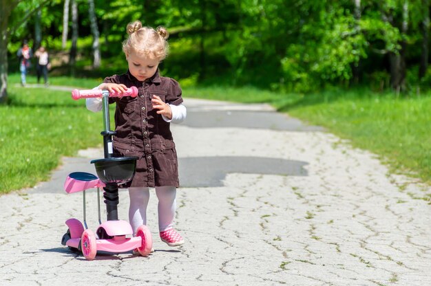 Foto niña montando un scooter en el parque