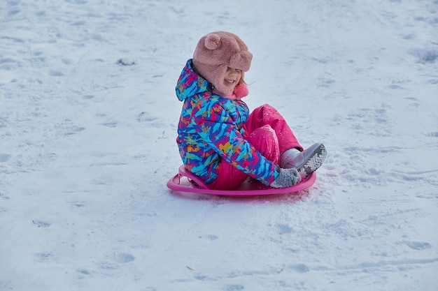 Niña montando en toboganes de nieve en invierno