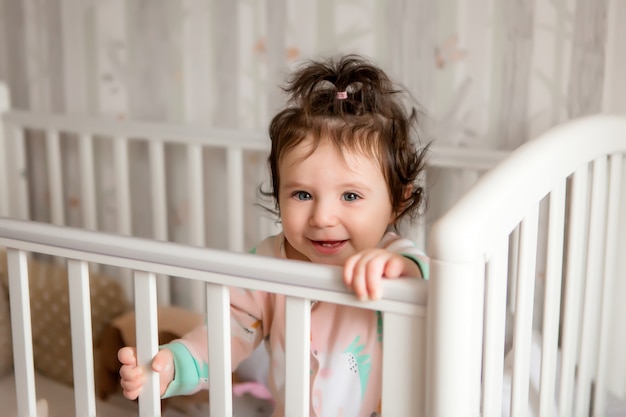 niña morena en la cama del bebé sonriendo