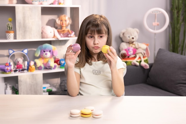 La niña morena joven no puede tomar la decisión correcta y elegir qué macarrón morder primero