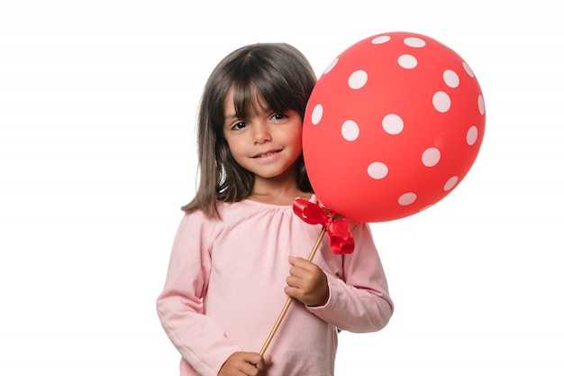 Niña morena sonriendo a la cámara con un globo