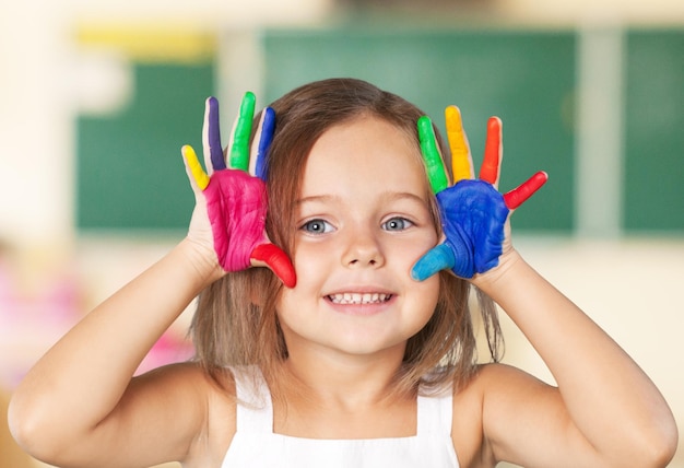 Foto niña mostrando manos pintadas sobre fondo brillante