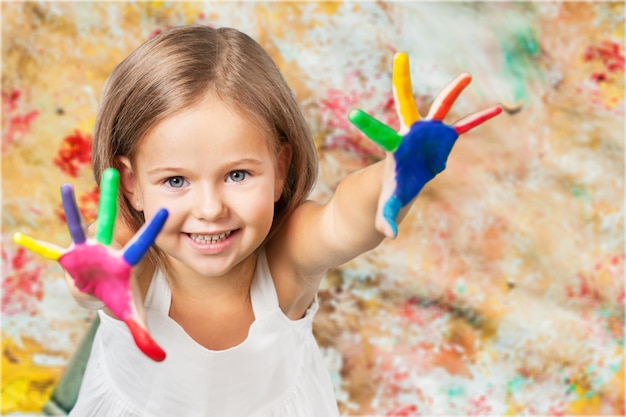 Niña mostrando manos pintadas sobre fondo de colores