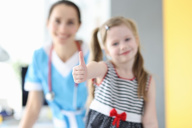 Niña mostrando el pulgar hacia arriba en la cita con el médico closeup