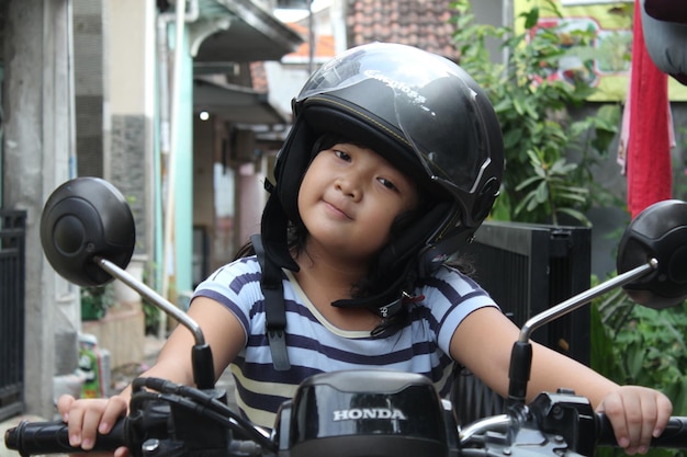 Foto niña en una moto y con casco