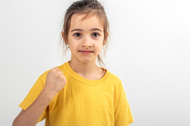 La niña muestra el puño en un fondo blanco aislado