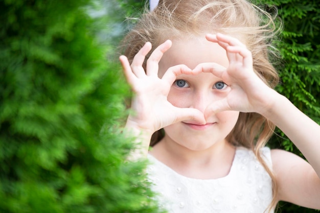 Una niña muestra un signo de corazón con los dedos.