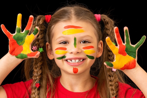 Una niña muestra sus manos manchadas con pinturas gouache.