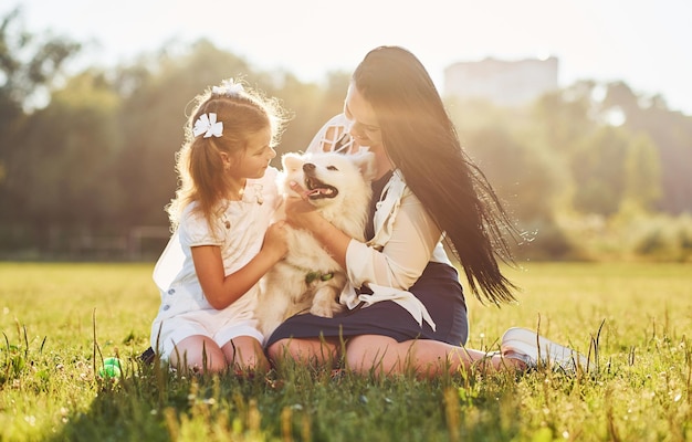 Niña y mujer tumbadas en el césped con su lindo perro