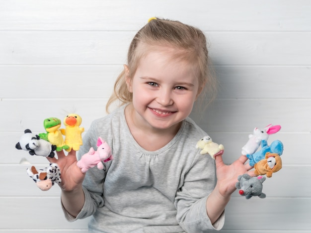 Niña con muñecos de muñecas en sus manos