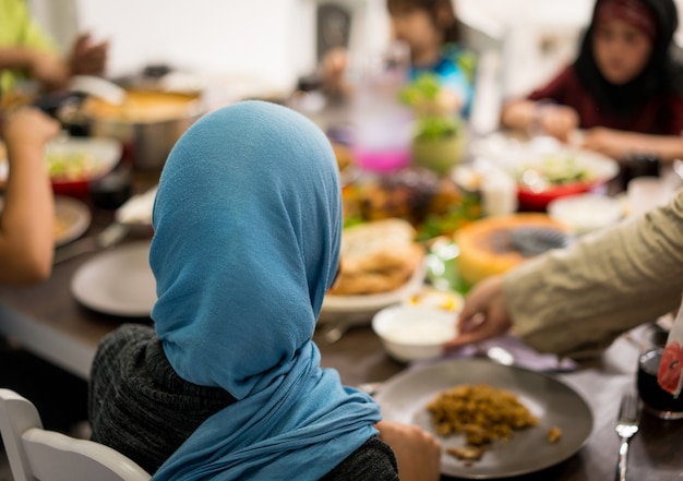Niña musulmana cenando en casa con su familia