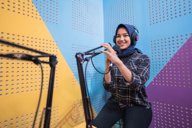 Niña musulmana está grabando un podcast en su estudio