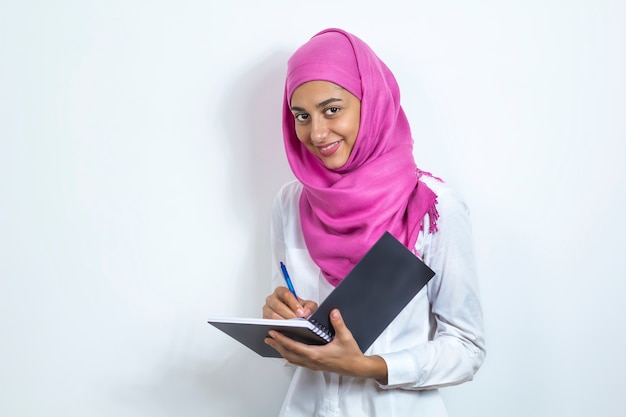 Una niña musulmana feliz en un hijab tiene un cuaderno en sus manos. Feliz mujer de negocios asiáticos.