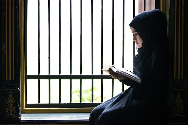 Una niña musulmana se puso un pañuelo negro en la cabeza Estaba leyendo textos islámicos. estrictamente