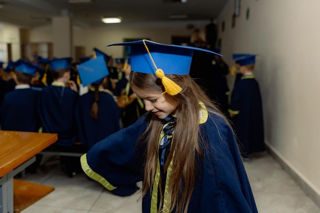 una niña muy alegre y feliz en un uniforme de primer grado sonríe dulcemente para la cámara durante una celebración escolar