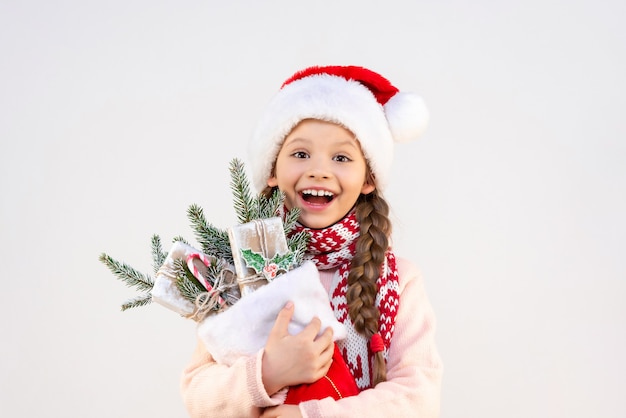 Una niña muy alegre sostiene los regalos y adornos de Año Nuevo en sus manos.